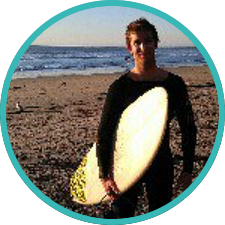 Ryan Kotzebue standing on the beach with a surfboard.